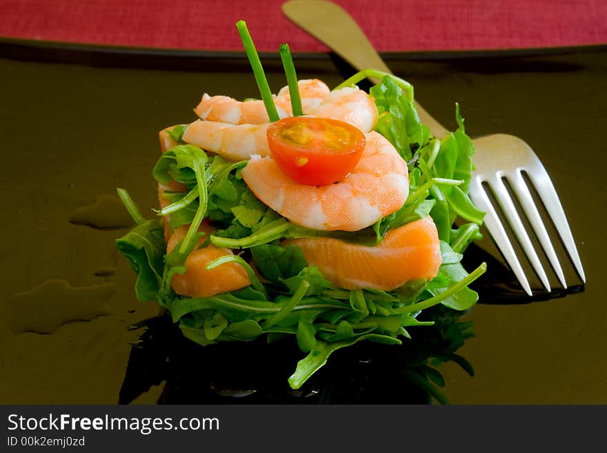 Fresh salmon tartar on black platter with rocket salad