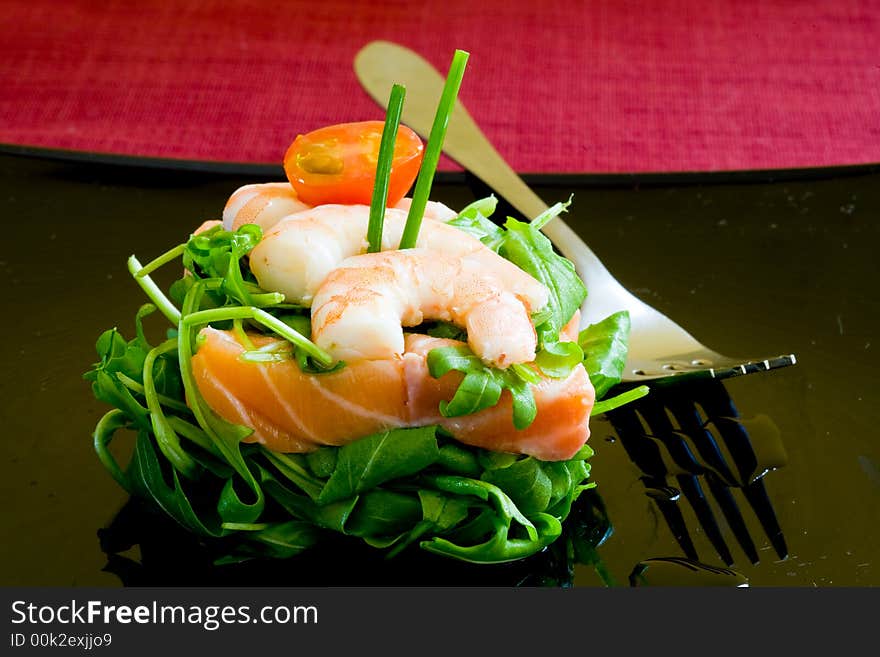 Fresh salmon tartar on black platter with rocket salad