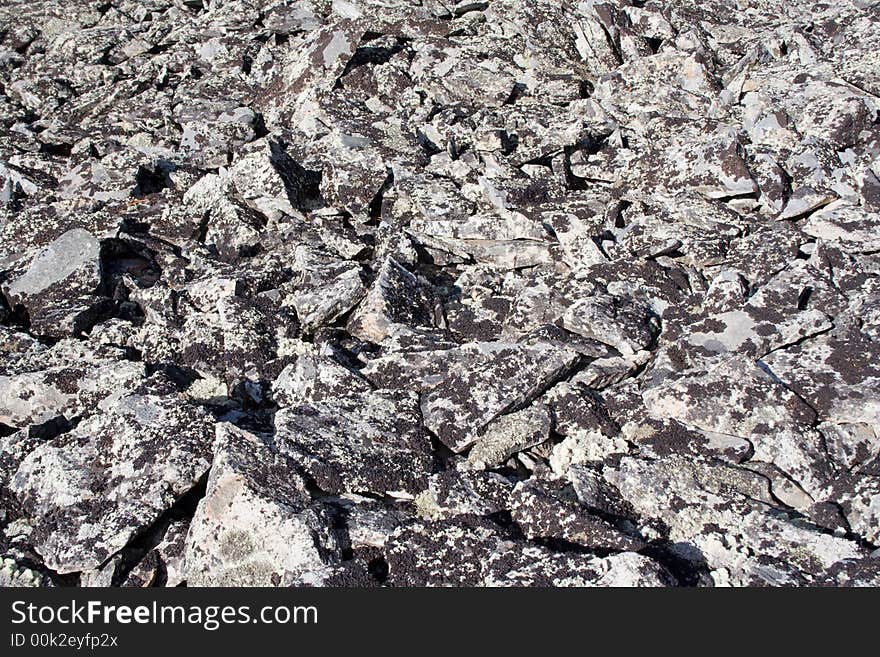 Lifeless rocky top of mountain with dry lichen over stones as a background