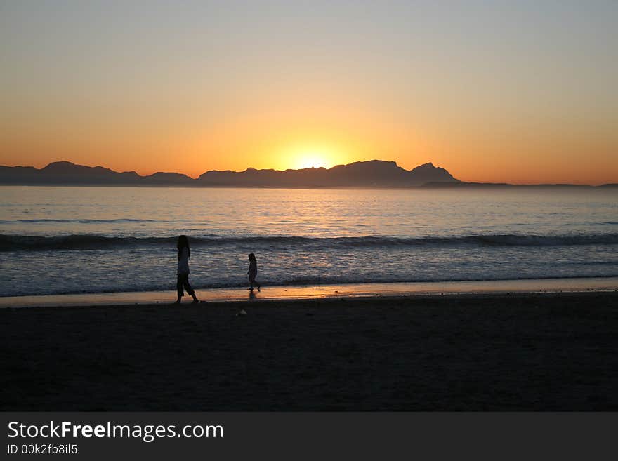 Mother & Daughter walking on the beach as the sun sets. Mother & Daughter walking on the beach as the sun sets