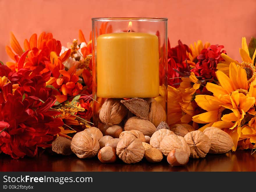 A candle with nuts in an autumn setting