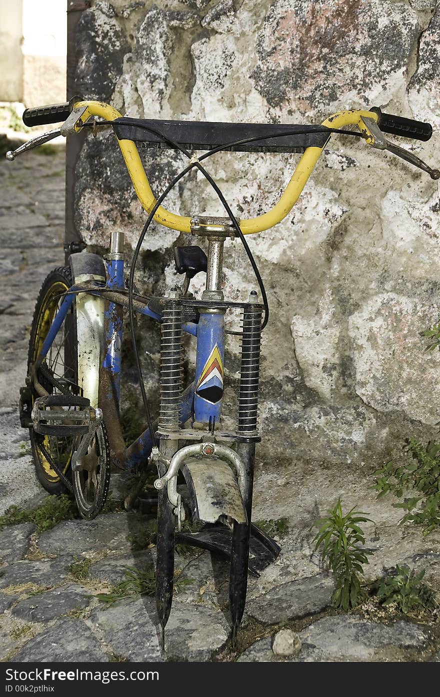 An old, rusty, broken bicycle without one wheel