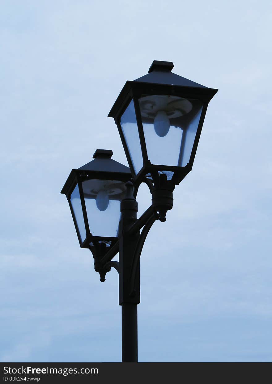 Old fashioned street lamps against clear blue sky. Evening. Twilights. Fires will light up soon.