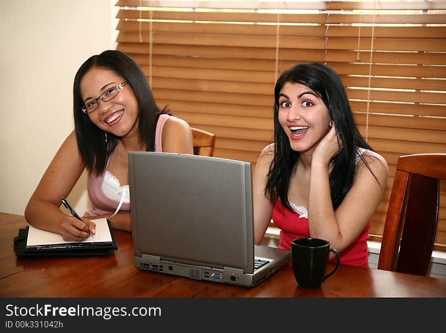 Two young women (middle eastern and chinese indonesian) with laptop at home. Focus on girl on right. Two young women (middle eastern and chinese indonesian) with laptop at home. Focus on girl on right.