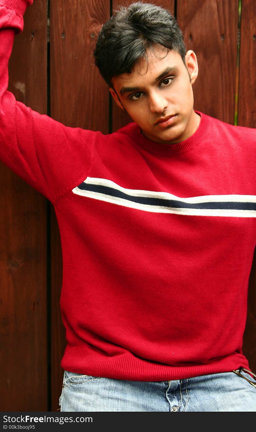 Fashion shoot of young indian man posing with wood background