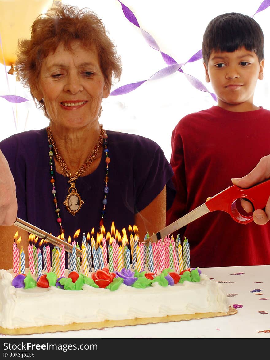 Two hands light the candles on an eighty-year-old woman's cake white her great grandson looks on. Isolated on white. Two hands light the candles on an eighty-year-old woman's cake white her great grandson looks on. Isolated on white.