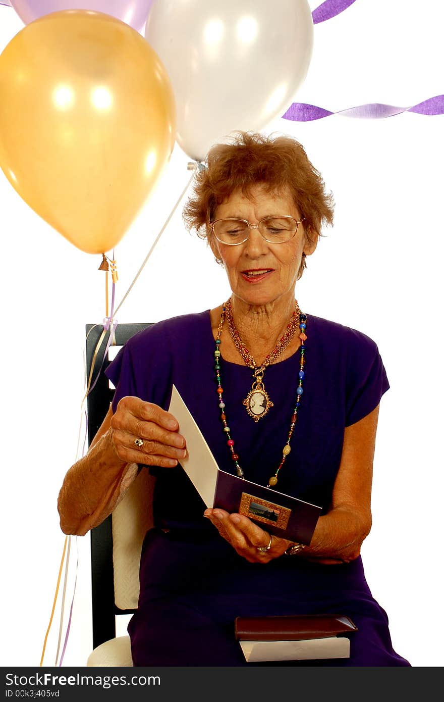 An eighty-year-old reading a card at her birthday party.  Isolated on white. An eighty-year-old reading a card at her birthday party.  Isolated on white.