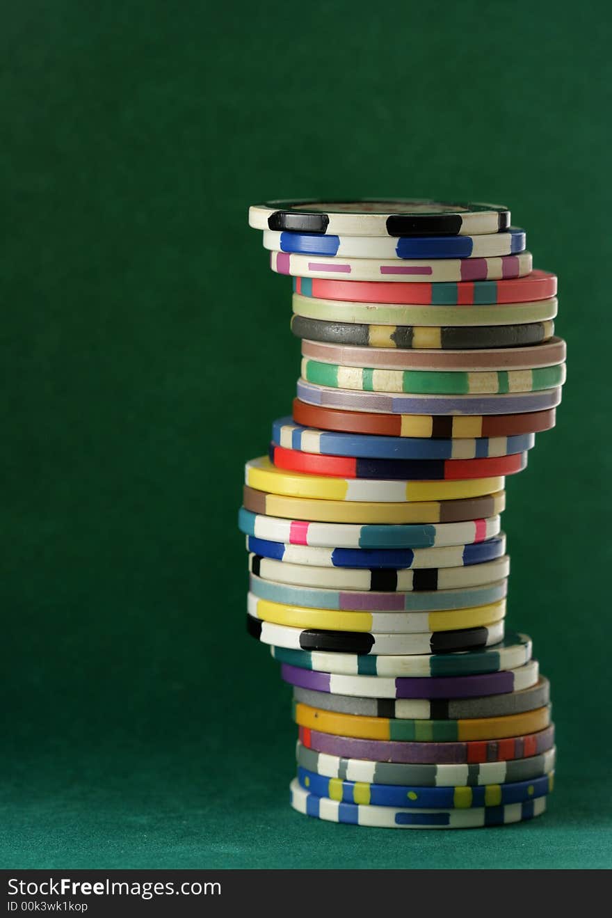 Stack of colorful casino chips over dark green background