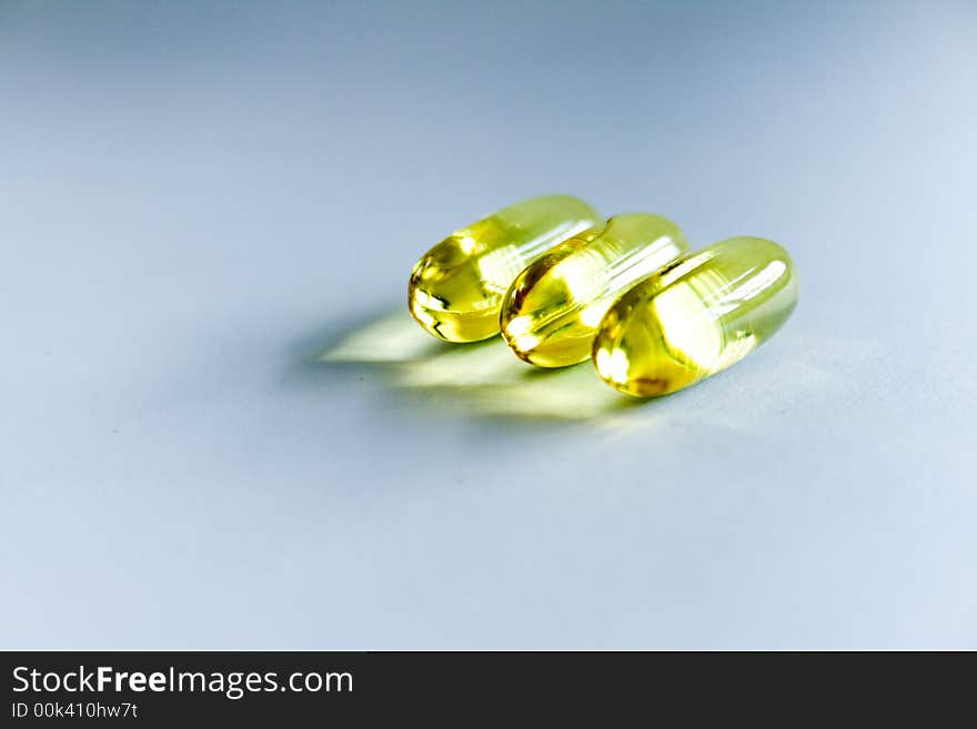 Three transparent yellow pills on white background