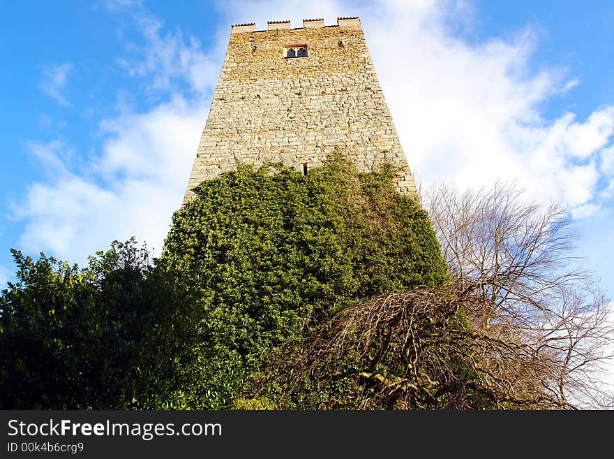 Old stone watching Tower. Partially covered by Ivy . Blue sky and clouds as background . Bavaria , April 2007. Old stone watching Tower. Partially covered by Ivy . Blue sky and clouds as background . Bavaria , April 2007.