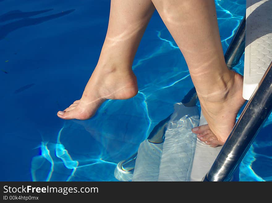 Woman foot with red nails in the swimming pool