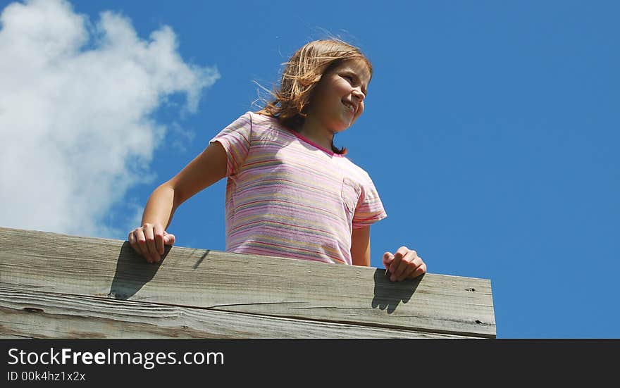 A little girl looking off the side of a playground. A little girl looking off the side of a playground.