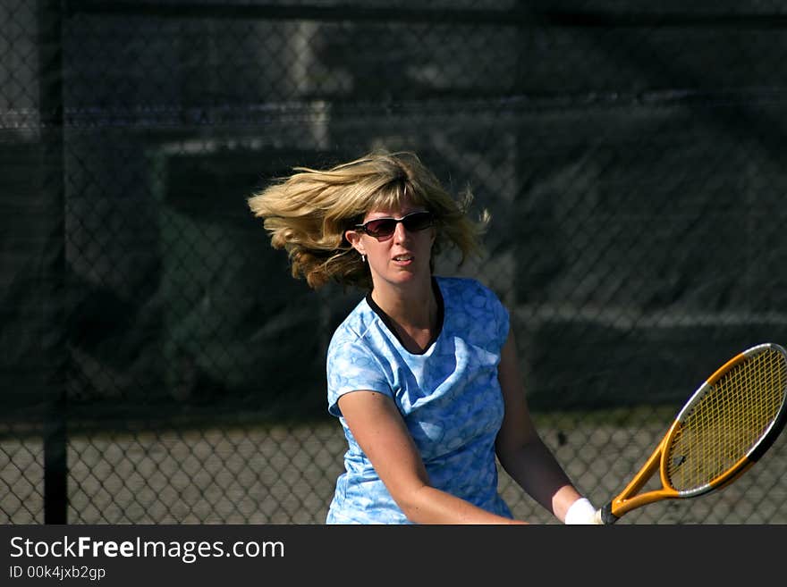 expressive face of female tennis player hitting the ball