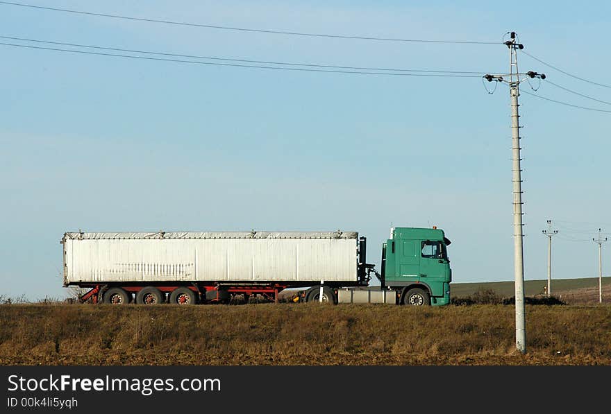 A white and green truck on a road a. A white and green truck on a road a