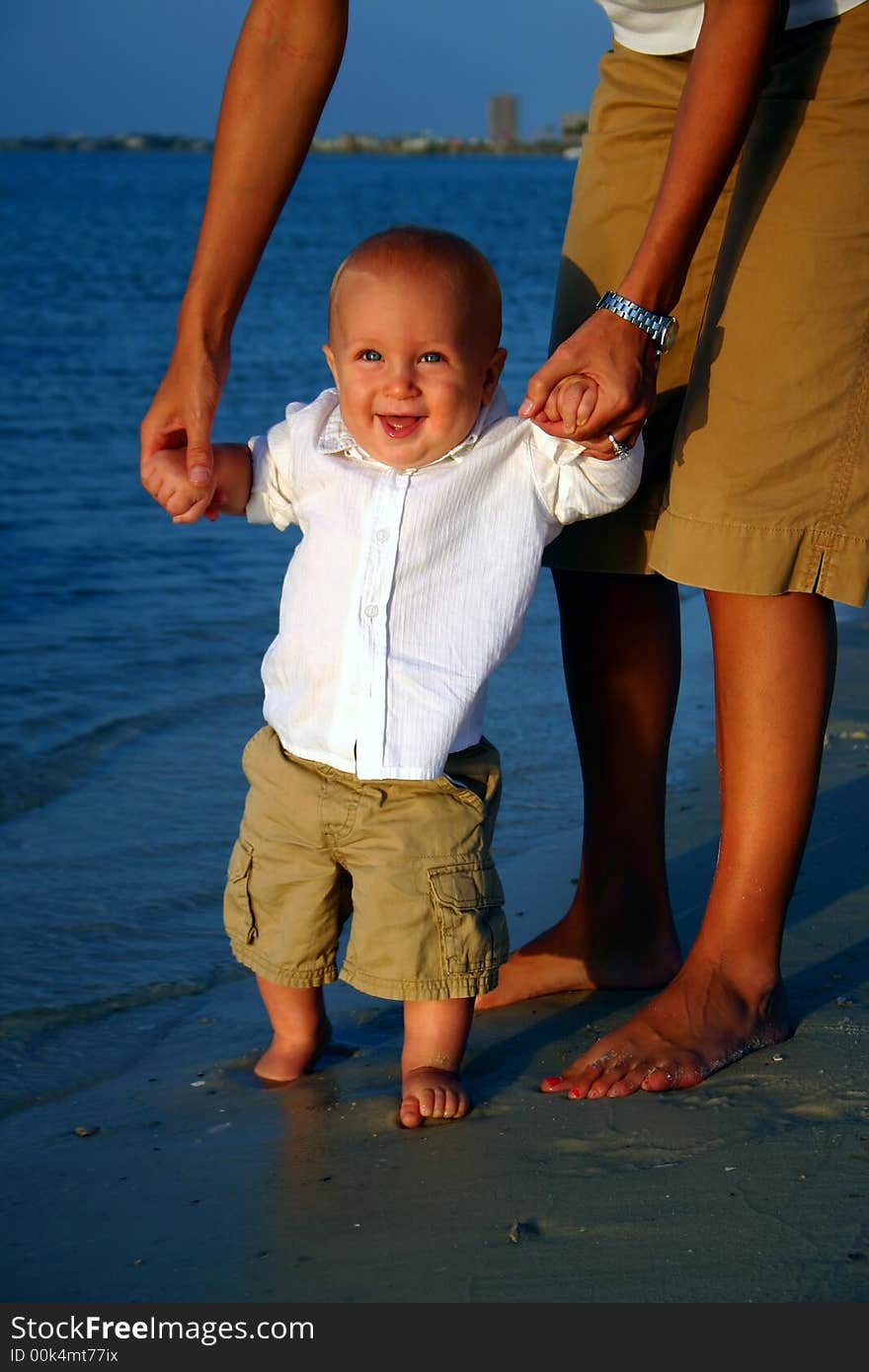 Blonde boy standing in the water on the beach laughing. Blonde boy standing in the water on the beach laughing