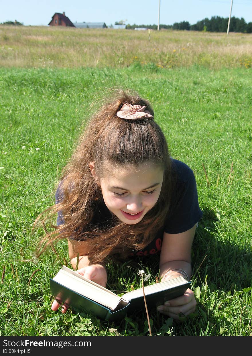 The young smile girl with book on the grass. The young smile girl with book on the grass