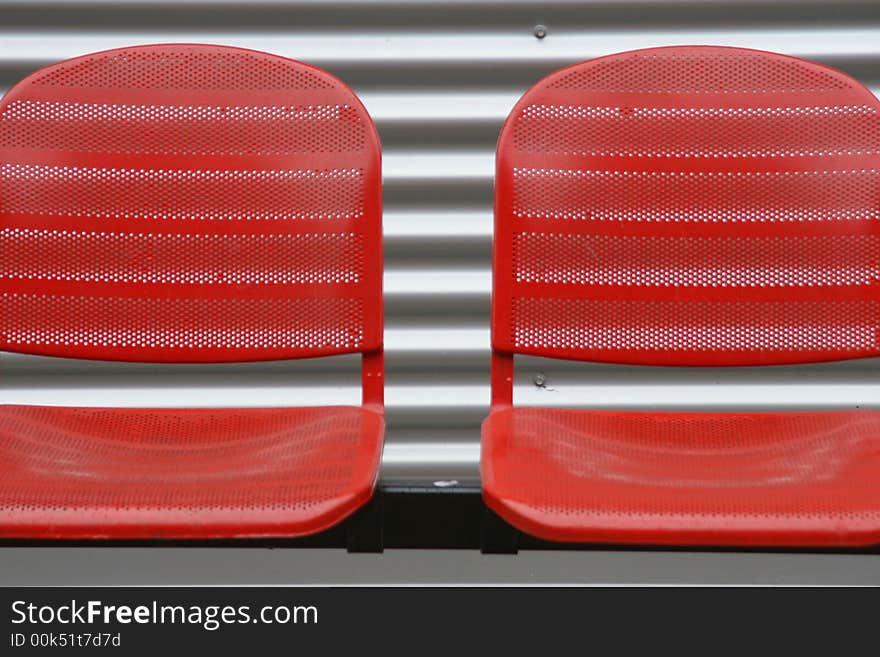 Close up of red chairs in front of a steel wall. Close up of red chairs in front of a steel wall