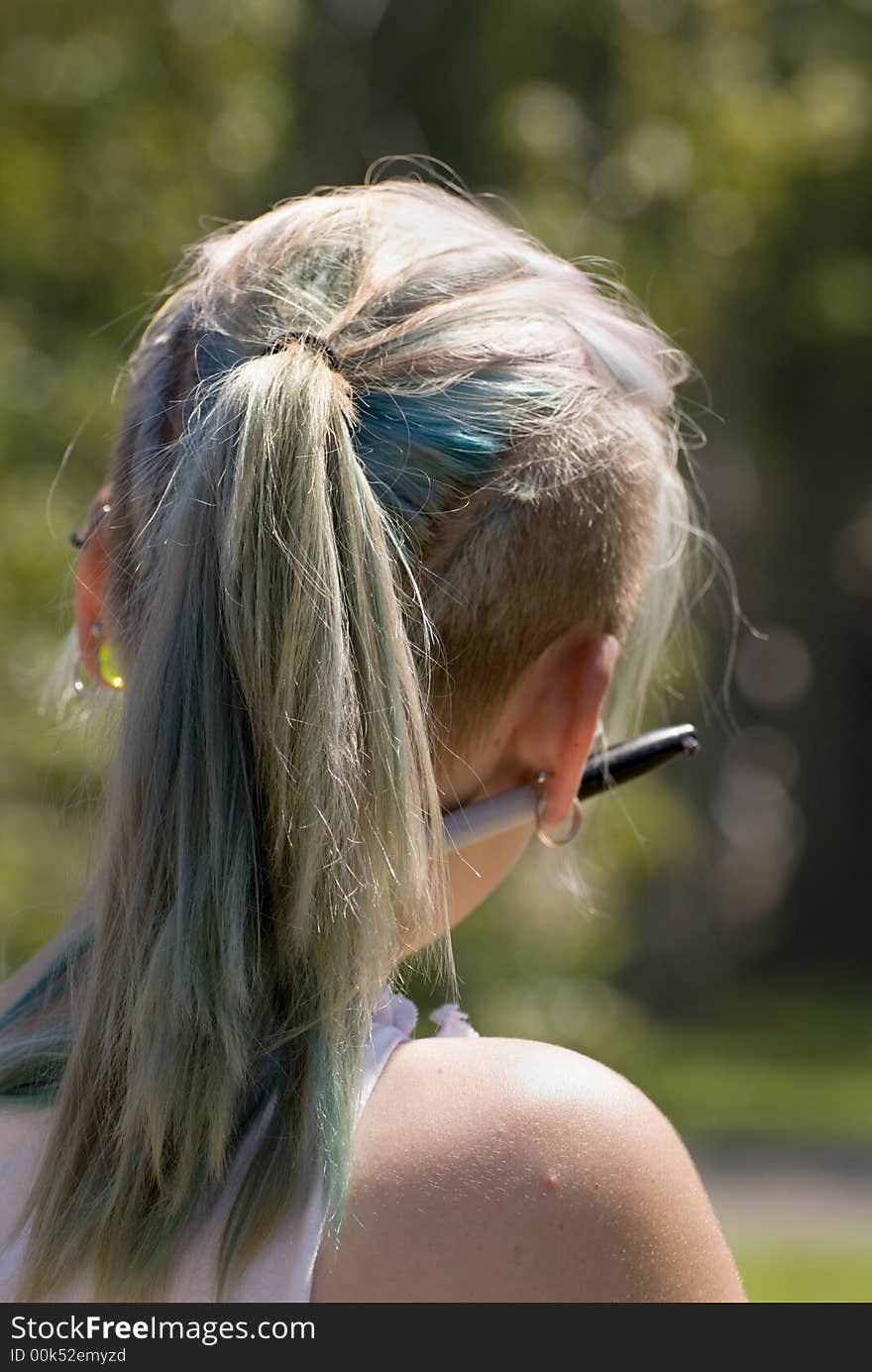 Young girl with colored hair and ornaments through her ears takes in the sun. Young girl with colored hair and ornaments through her ears takes in the sun.