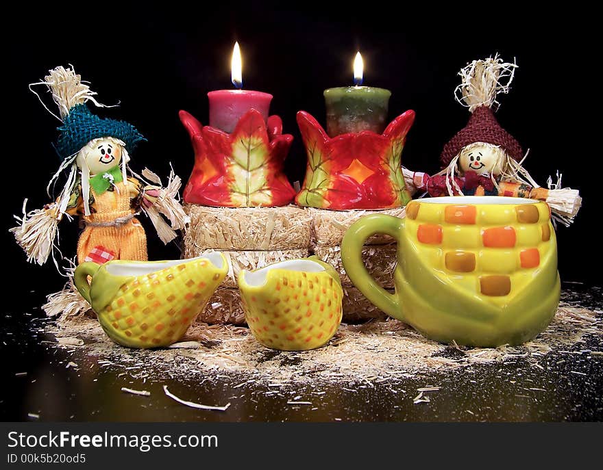 Scarecrows, hay bales, candles, and autumn ceramics make this a beautiful autumn display.  Black background. Scarecrows, hay bales, candles, and autumn ceramics make this a beautiful autumn display.  Black background.