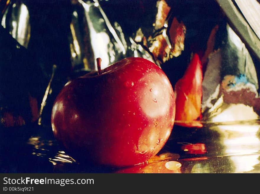 Composition with an apple Gold background Brightly red apple Artificial light Light-shadow-reflexes Drops of water on an apple healthful