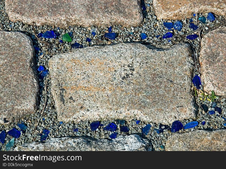 Pavement with blue and green pieces of broken glass