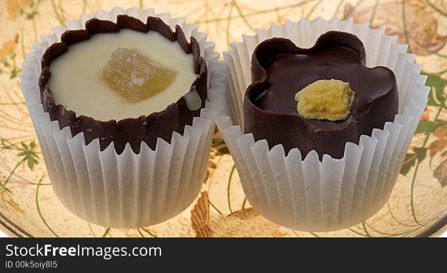 Two chocolates with a fruit stuffing on a dish from transparent brown glass. Two chocolates with a fruit stuffing on a dish from transparent brown glass