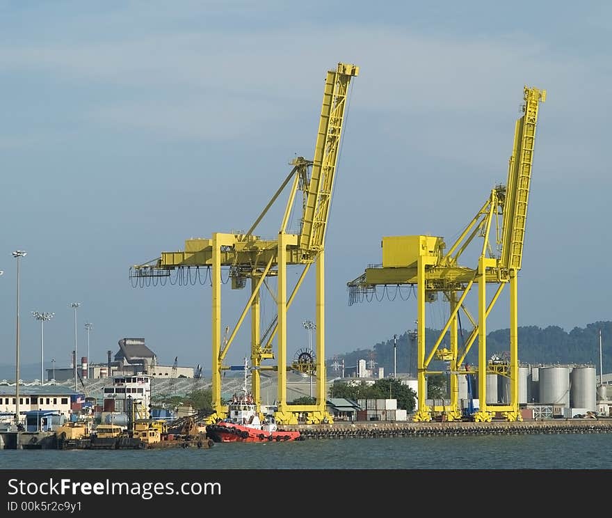 Two large, yellow container cranes at an industrial harbour. Two large, yellow container cranes at an industrial harbour.