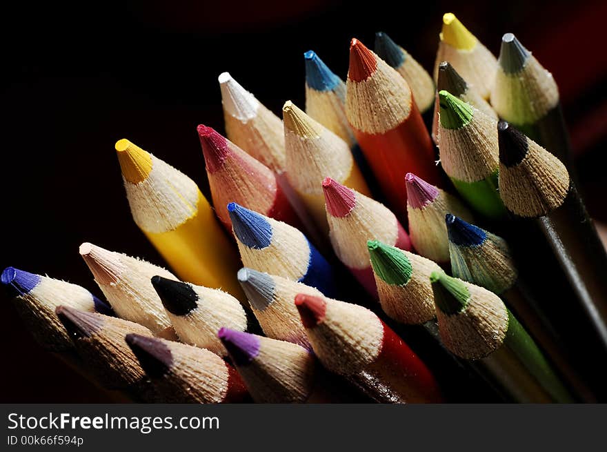 Colorful assortment of drawing pencils bunched together against a dark background. Colorful assortment of drawing pencils bunched together against a dark background