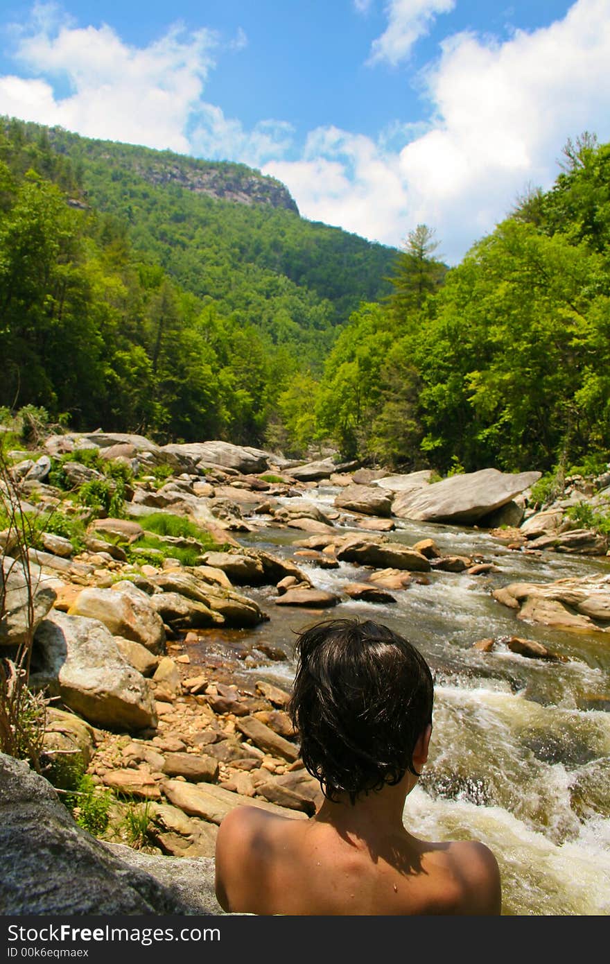 Boy gazing upriver through green gorge. Boy gazing upriver through green gorge