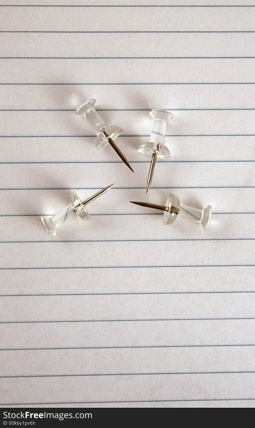 A group of thumbtacks on a piece of lined paper