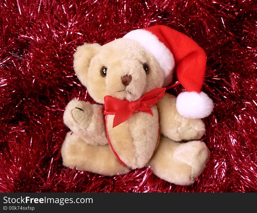 Photo of a stuffed christmas bear tree ornament wearing a santa hat on red garland