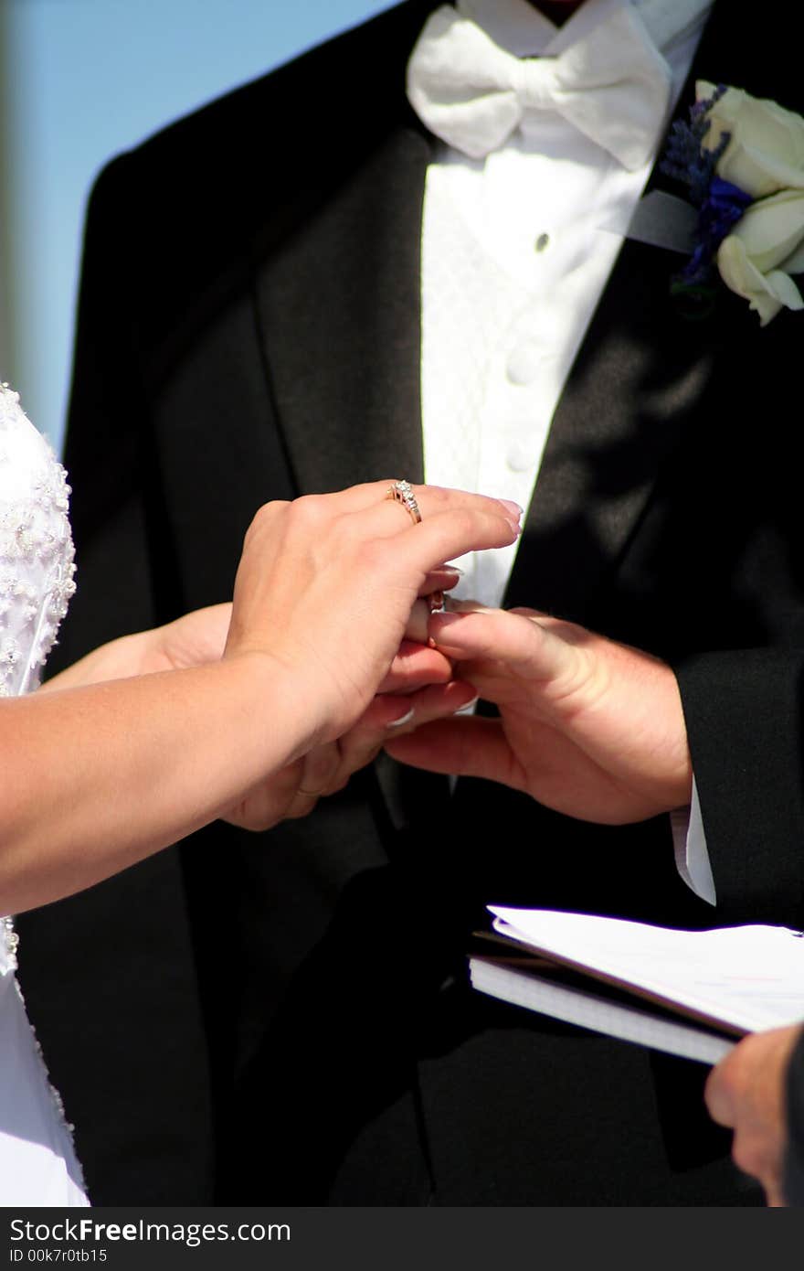 Close up of Bride placing the ring on grooms finger. Close up of Bride placing the ring on grooms finger