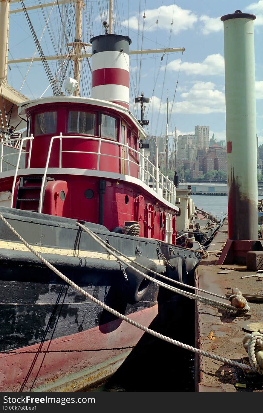 Old tug boat tied up to a rusting barge at the South Street Seaport NYC. Brooklyn is across the river in the background. Old tug boat tied up to a rusting barge at the South Street Seaport NYC. Brooklyn is across the river in the background.