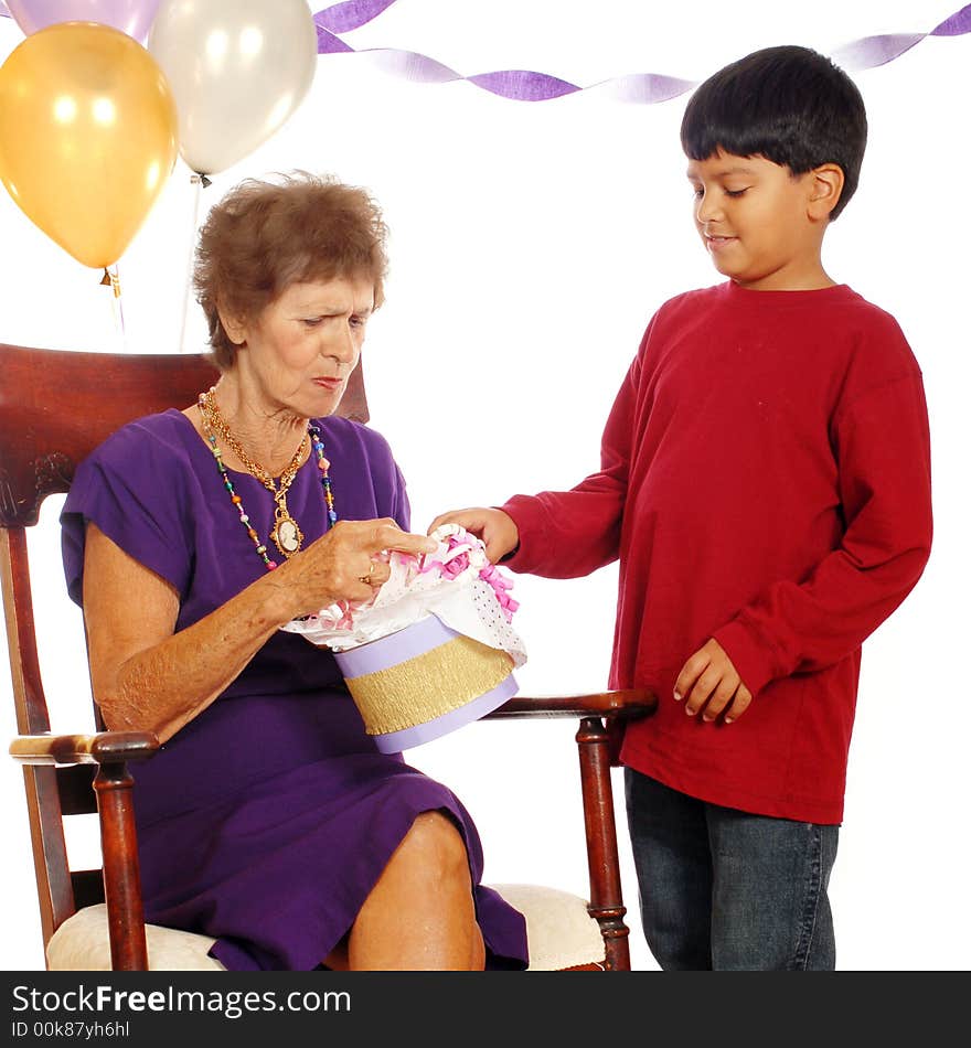 Senior woman accepting a gift from her great grandson at a celebration of her 80th birthday. Senior woman accepting a gift from her great grandson at a celebration of her 80th birthday.