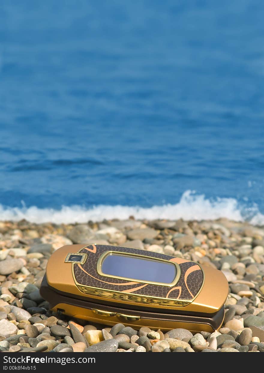 Mobile phone on beach, sea on background