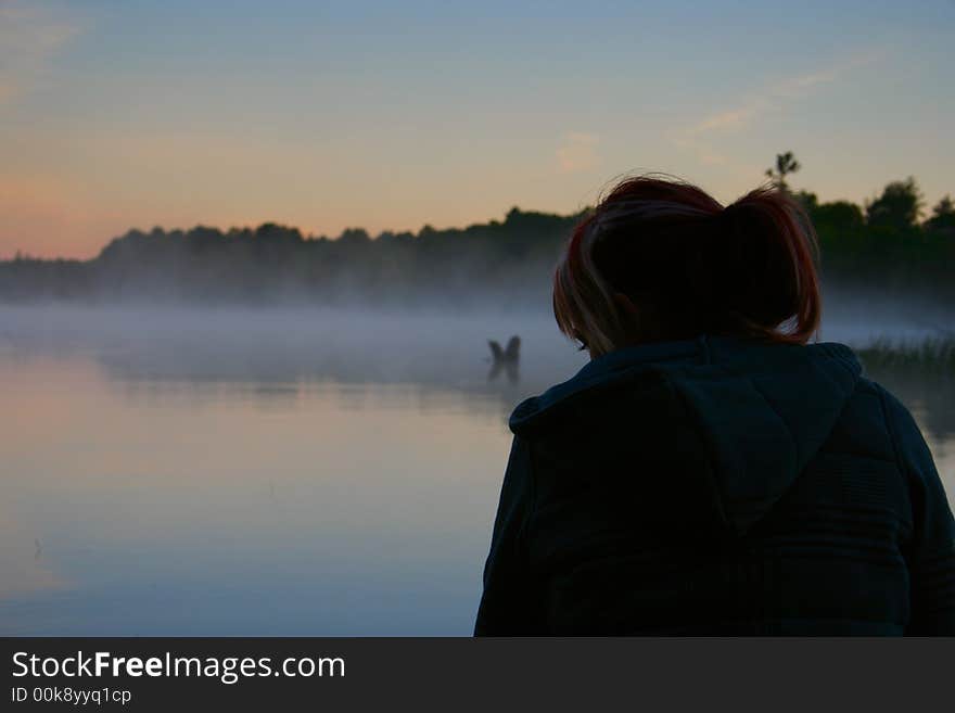 Thoughtful girl looking out to sunrise on lake muskoka. Thoughtful girl looking out to sunrise on lake muskoka