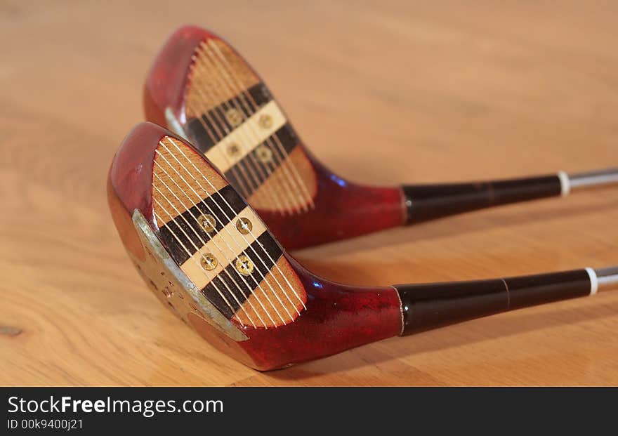 Two old golf clubs on a hardwood floor. Two old golf clubs on a hardwood floor