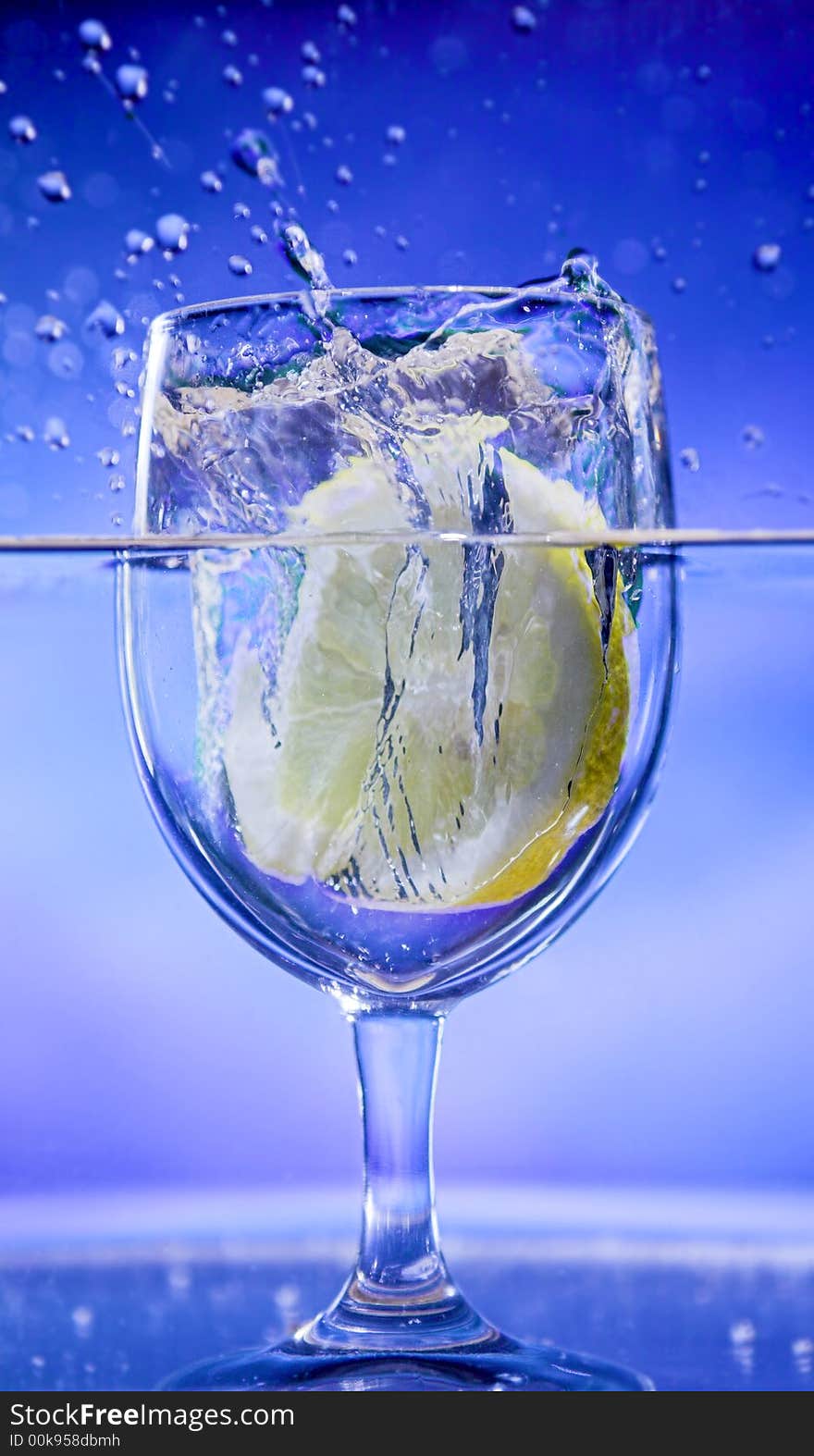 Lemon splash in transparent glass over blue background. Lemon splash in transparent glass over blue background