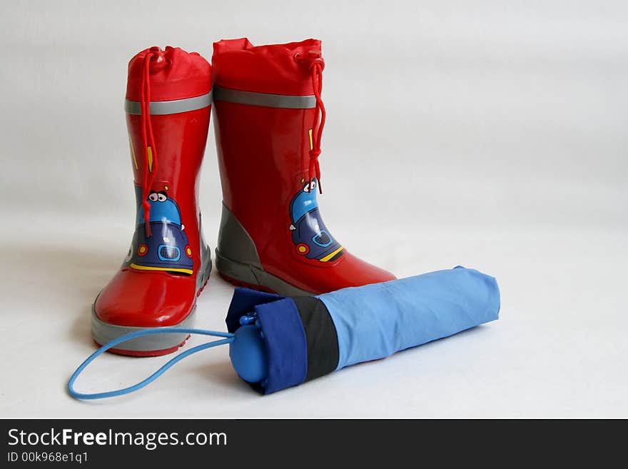 Red wellington boots and blue umbrella isolated on white background