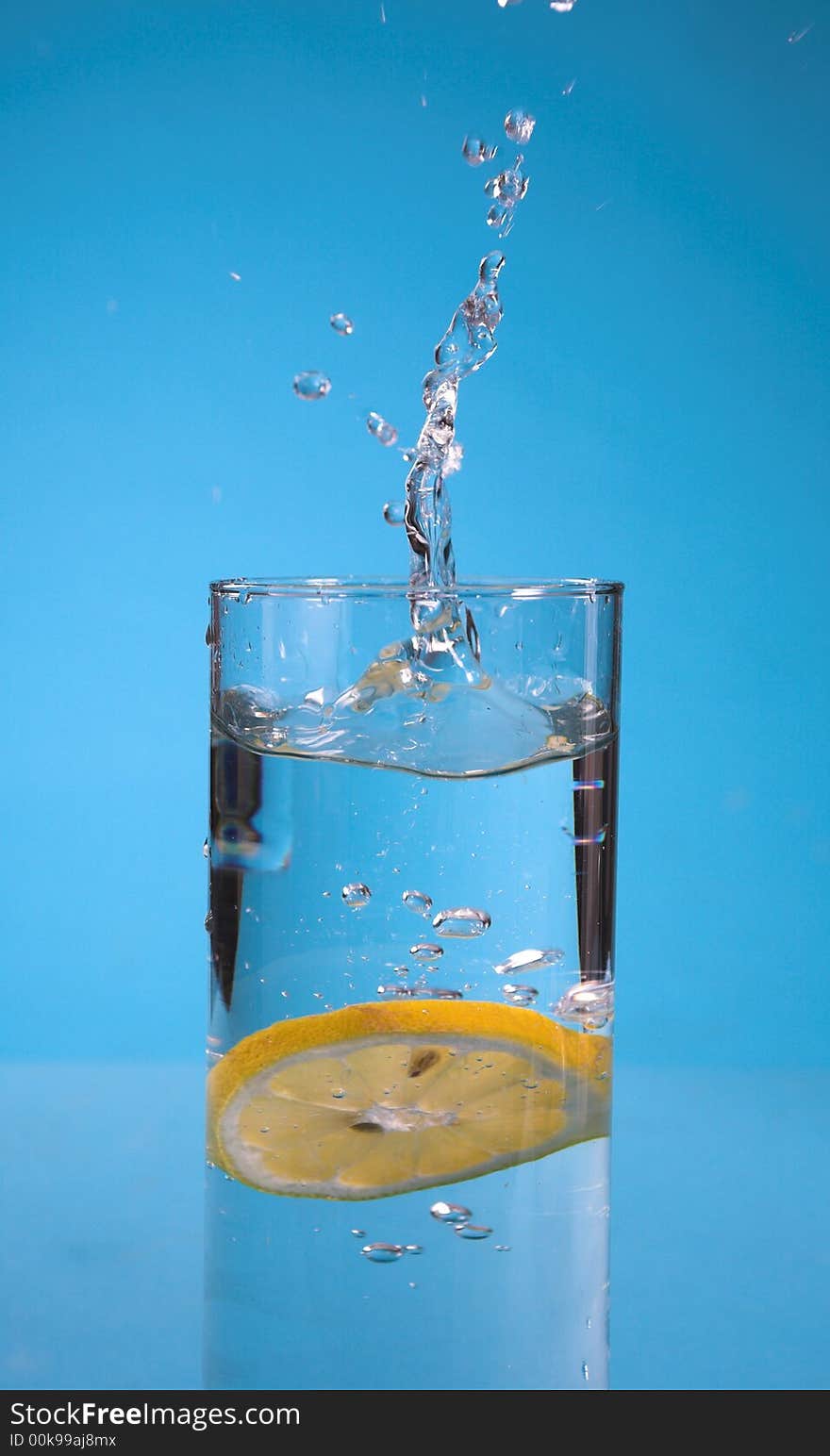 Lemon splash in transparent glass over blue background