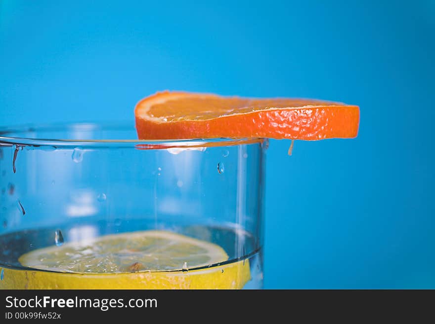 Oranges and lemons in transparent glass over blue background