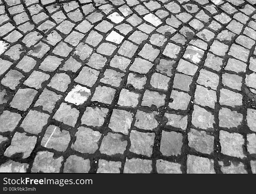 Background of cobblestone pavement to convey the idea of unevenness, circular pattern, with tufts of grass and dirt sticking out. Background of cobblestone pavement to convey the idea of unevenness, circular pattern, with tufts of grass and dirt sticking out.