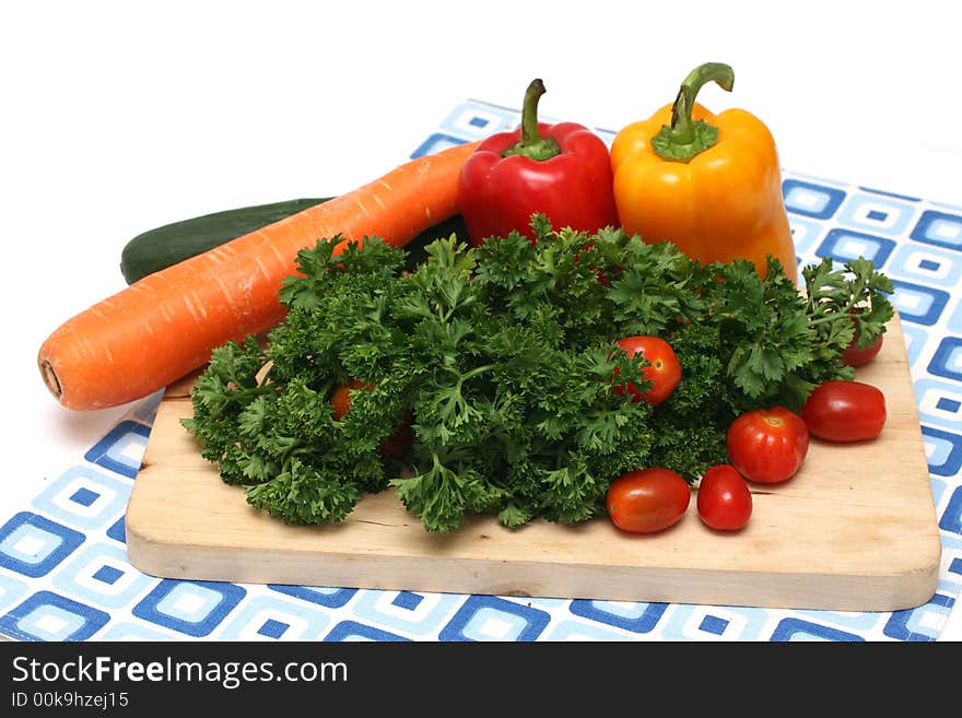 Parsley, cherry tomatoes, capsicums, carrot and cucumber on wooden board. Parsley, cherry tomatoes, capsicums, carrot and cucumber on wooden board