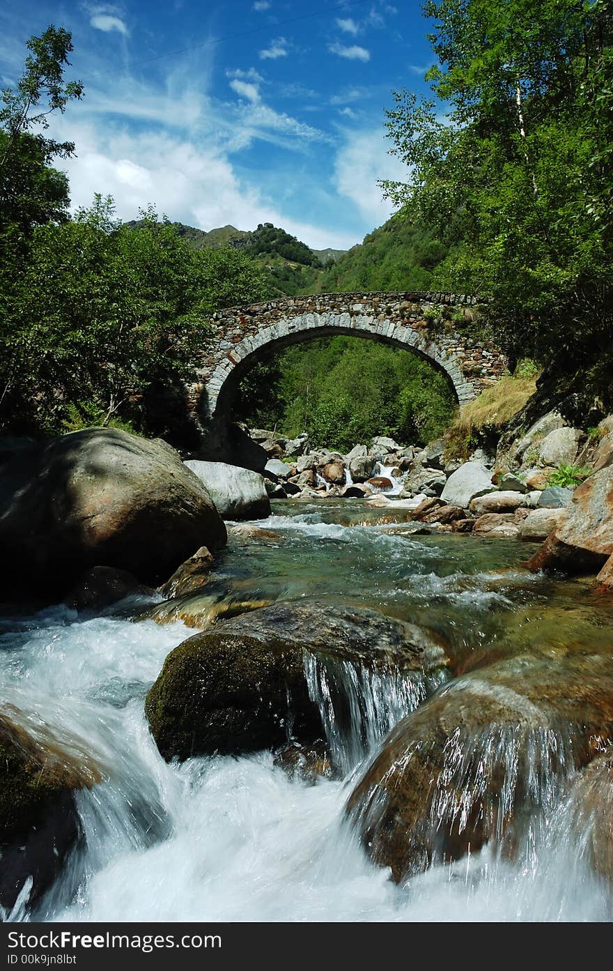 Aged arch bridge over a small mountain river