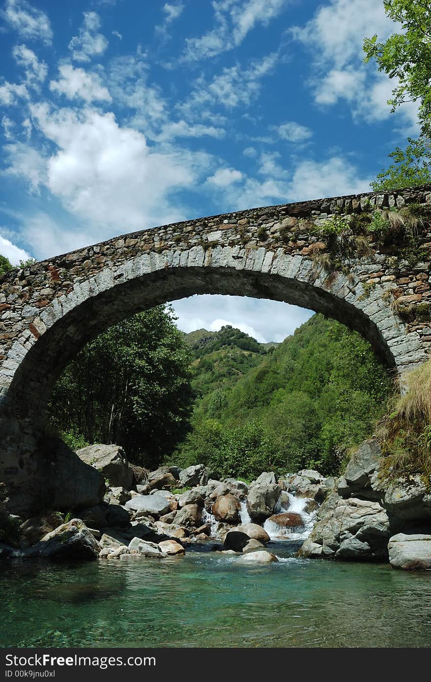 Aged arch bridge over a small mountain river