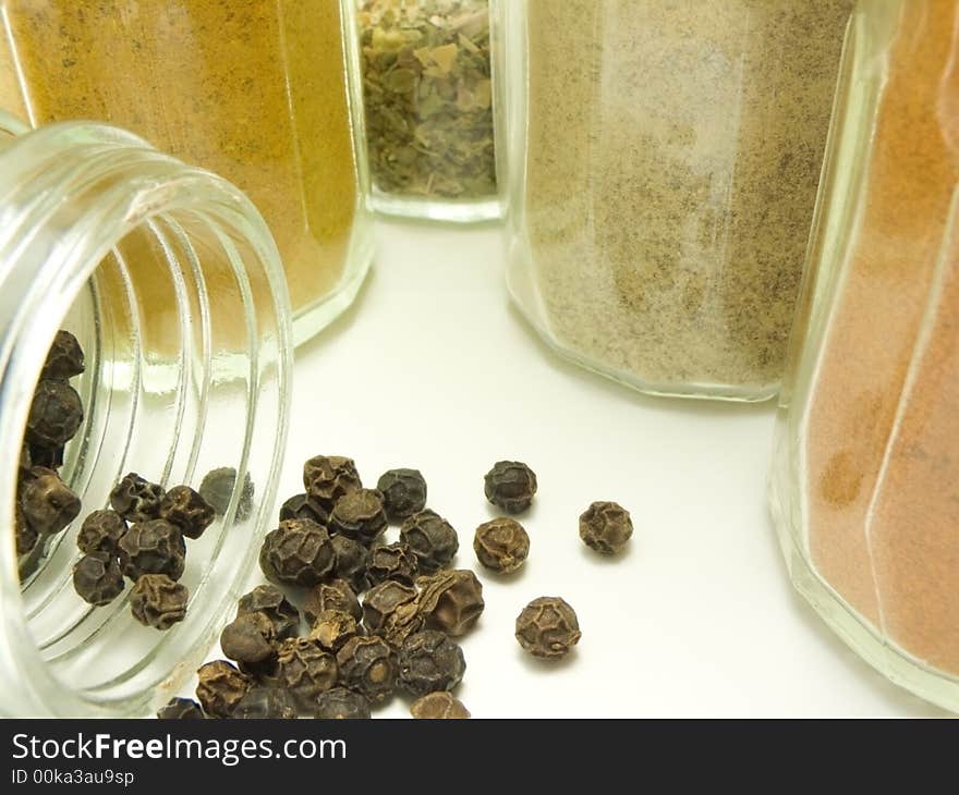 Ground spices in glass tableware and whole black pepper