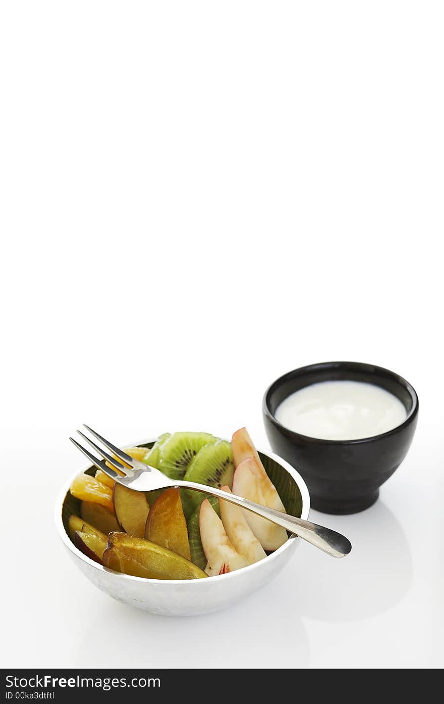 Fruits with yoghurt dip over a white background (lots of copy space)