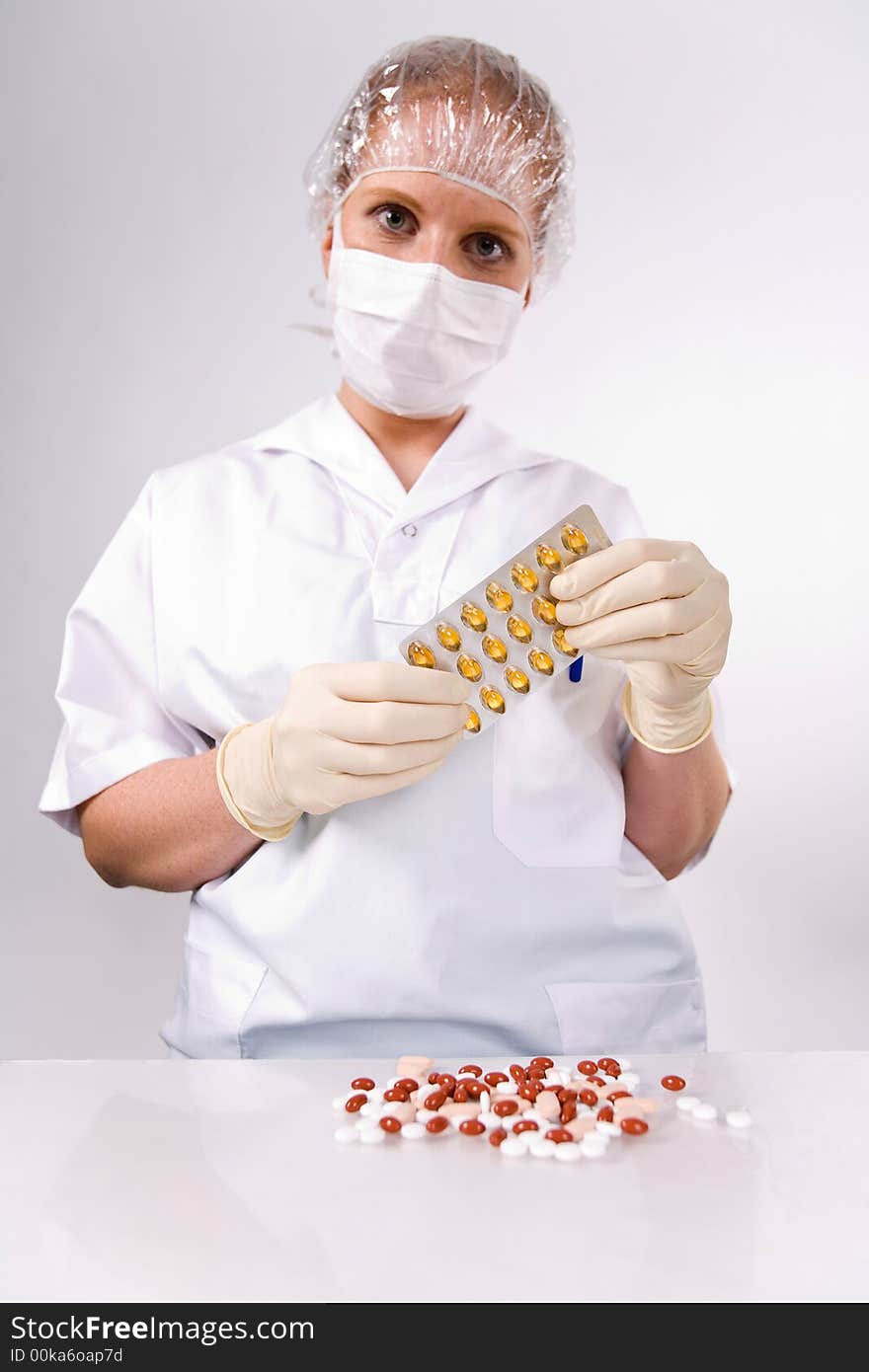 Woman with Blister-card in hand and many pills and a scad with pills. Hygienic white. Looking into camera. Woman with Blister-card in hand and many pills and a scad with pills. Hygienic white. Looking into camera.