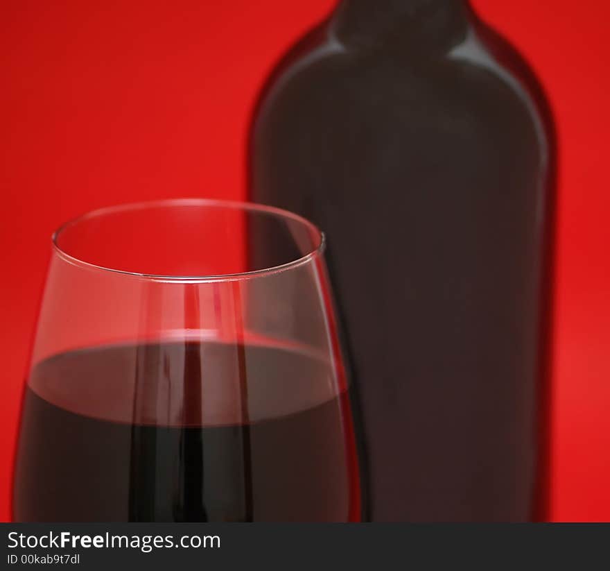 Glass and bottle of wine on the red background