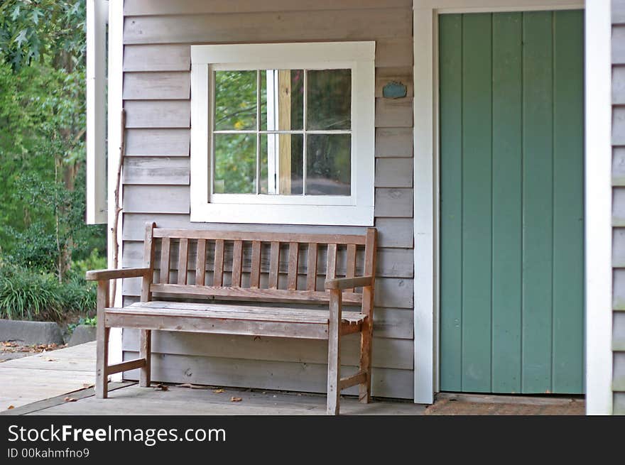 An old wooden bench on the porch of a small cabin. An old wooden bench on the porch of a small cabin